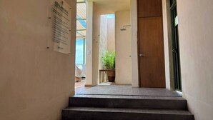 Un couloir d’hôtel avec une porte en bois, une plante en pot et un panneau sur le mur.