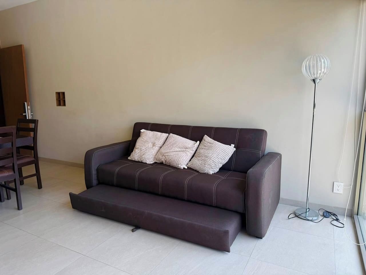 A modern living room with a dark brown sofa, a coffee table, and a floor lamp.