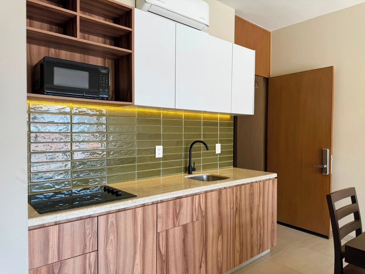 Una cucina con forno a microonde integrato, lavello e mobiletto in legno.