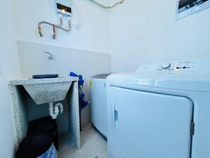 A laundry area with a washing machine, a utility sink, and a water heater. - 2-bedroom  spacious apartment in tranquil Punta Cana, very close to the mall (Punta Cana)