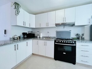 A kitchen with white cabinets, a black stove, and a granite countertop. - 2-bedroom  spacious apartment in tranquil Punta Cana, very close to the mall (Punta Cana)