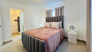 Ein Schlafzimmer mit Bett, Nachttisch und einer Tür zu einem Badezimmer.
