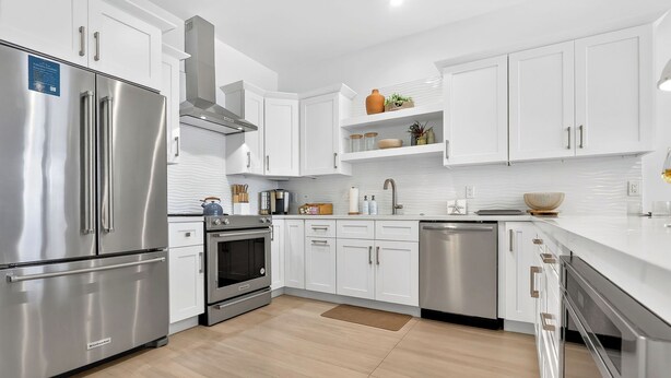 A modern kitchen with stainless steel appliances, white cabinetry, and a light wood floor. - The Lighthouse | Ocean and Pool Views, Game Room, Pool + Dock Access (Islamorada)