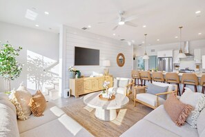 A modern living room with a round coffee table, sofas, and a TV mounted on the wall.