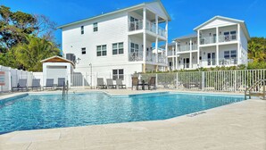 A pool area with a clear blue pool, white buildings with balconies, and a fenced patio. - The Lighthouse | Ocean and Pool Views, Game Room, Pool + Dock Access (Islamorada)
