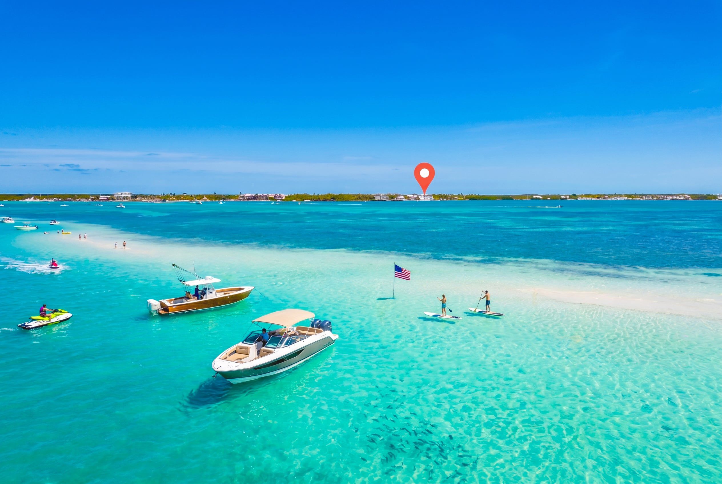 Une plage tropicale aux eaux turquoise et limpides, avec des bateaux et une rive sablonneuse.