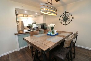 Un coin repas avec une table en bois, des chaises, un vase de fleurs et une décoration murale représentant une boussole.