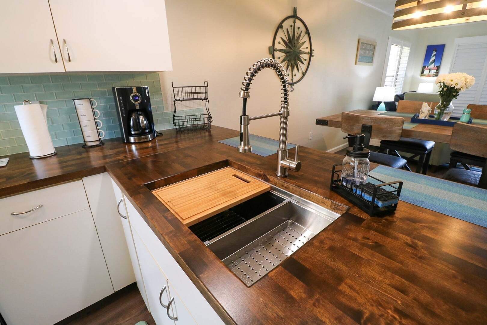 Eine Küche mit Spüle aus Edelstahl, einer Holz Arbeitsplatte und einer Kaffeemaschine.