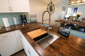 A kitchen with a stainless steel sink, wooden countertop, and a coffee maker. - Newly Remodeled Condo Ocean Village Club F26 (St. Augustine)