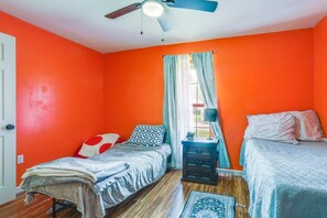 A room with two beds, a ceiling fan, a window with curtains, and a bedside table with a lamp. - Peaceful Baton Rouge Oasis Private Pool, Hot Tub & Fire Pit Near LSU! (Baton Rouge)