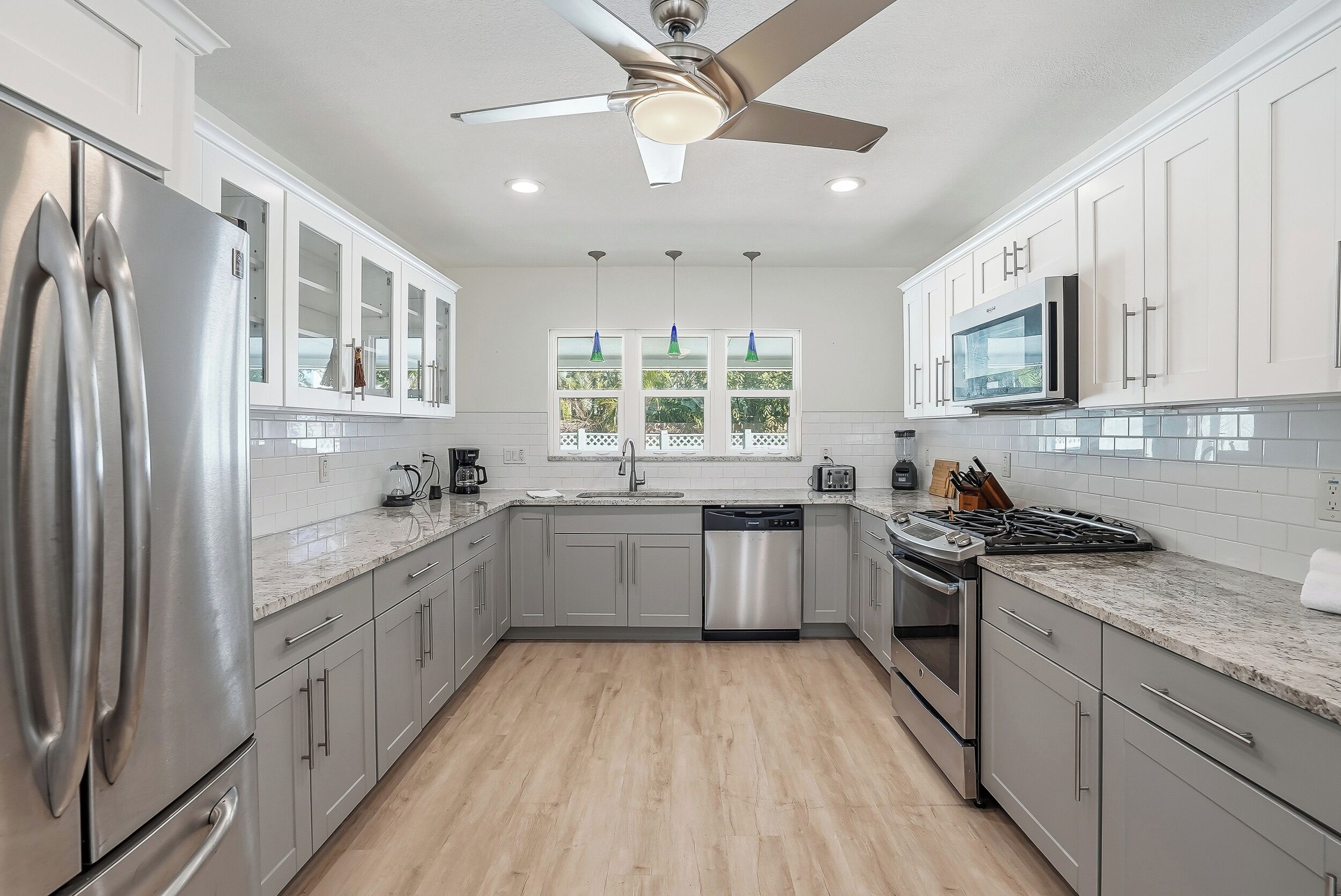 A modern kitchen with stainless steel appliances, white cabinetry, and a central island.