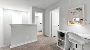 A hallway with a white bench, a desk with a lamp, and a framed inspirational quote on the wall. - Brand New 3BR Home with Game Room & BBQ Near The Woodlands (Decker Prarie)