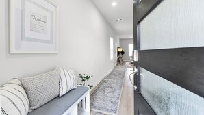 A hallway with a bench, a framed welcome sign, and a patterned rug. - Brand New 3BR Home with Game Room & BBQ Near The Woodlands (Decker Prarie)
