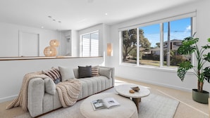 A modern living room with a sofa, a round coffee table, a large window, and a ceiling fan.