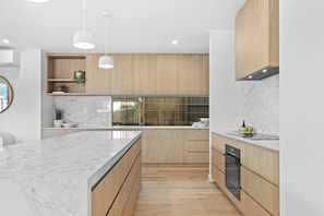 Una cocina moderna con encimeras de mármol, armarios de madera e iluminación colgante.