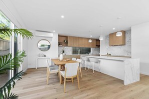Una cocina moderna con encimera de mármol, armarios de madera e iluminación colgante.