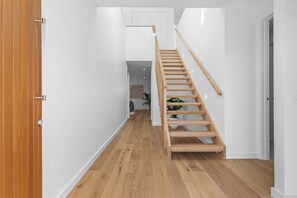 A wooden staircase in a hallway with white walls and wooden flooring.