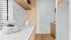 A modern kitchen with a marble countertop, wooden cabinets, and a built-in oven.