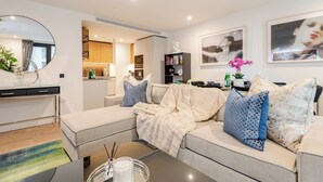 Ein modernes Wohnzimmer mit Sofa, Couchtisch und einer Küche im Hintergrund.