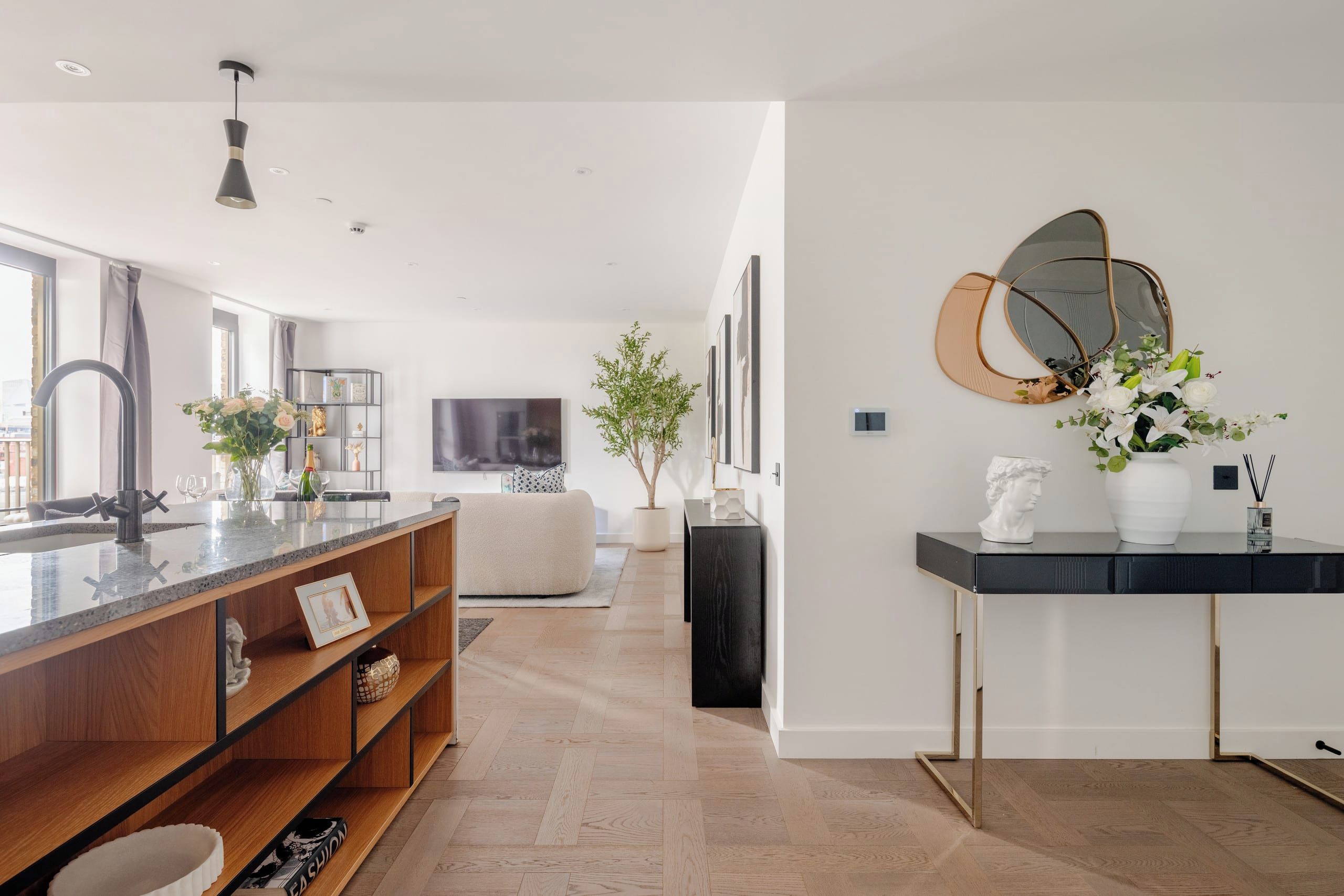 A modern kitchen with a central island, a dining area with a sofa, and a living room with a TV.