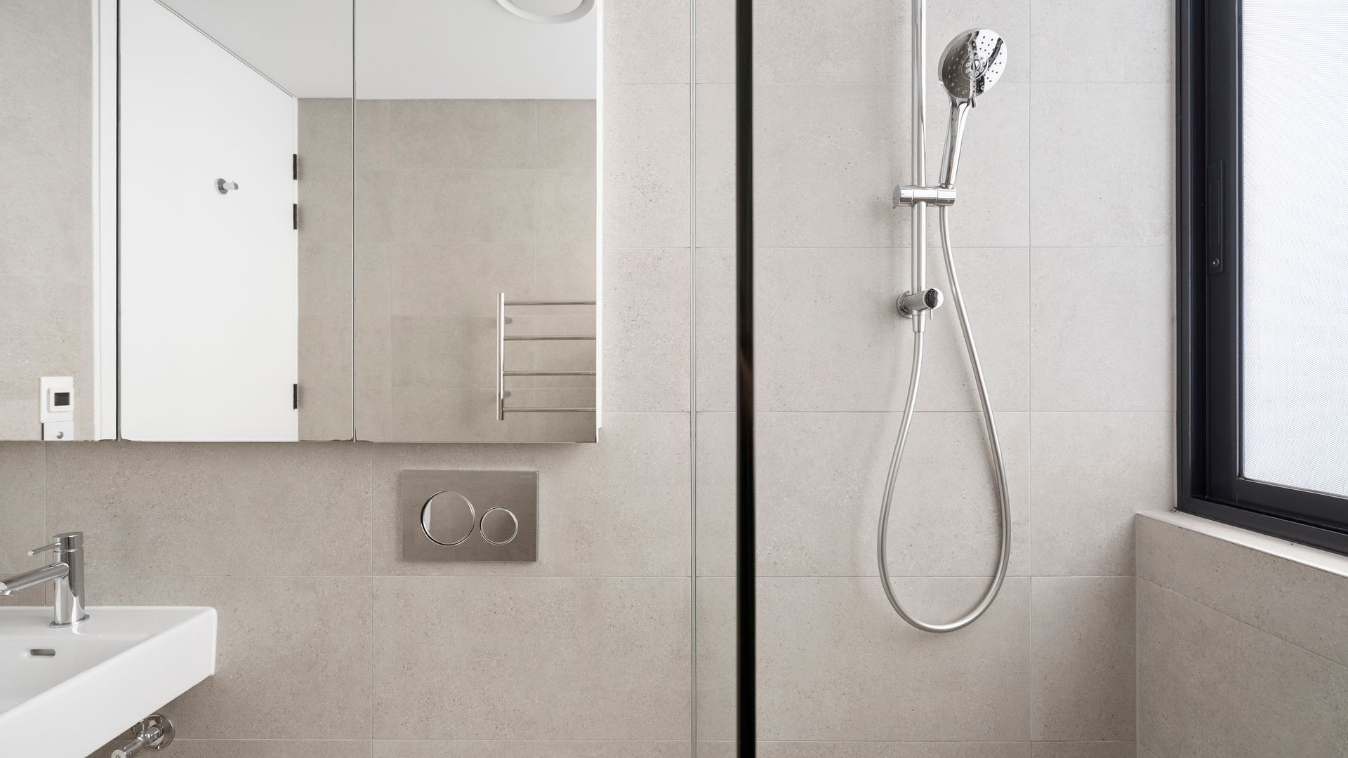 A modern bathroom with a shower, a sink, and a mirror.