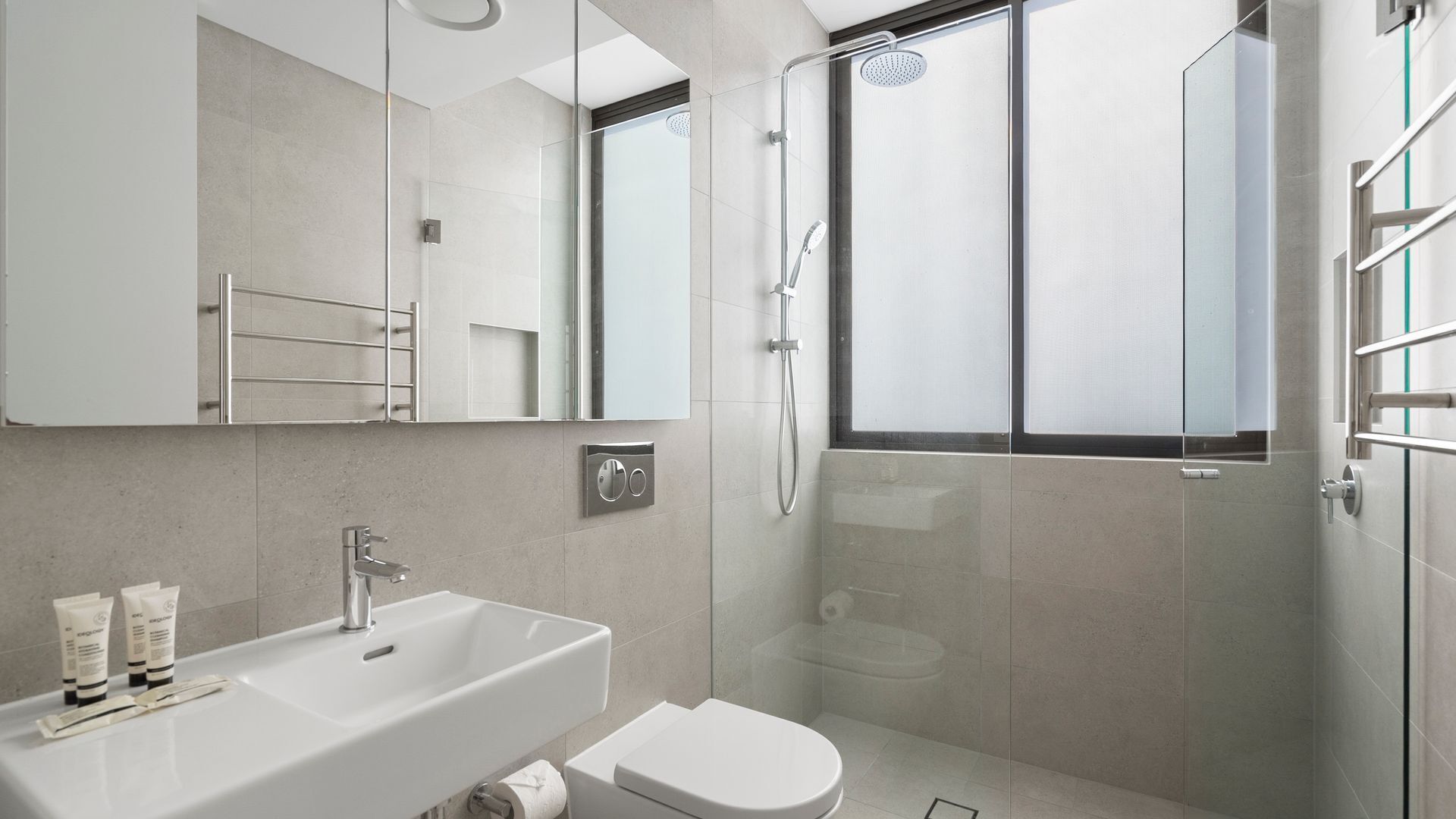Un baño moderno con un lavamanos grande, inodoro y ducha con mampara de vidrio.