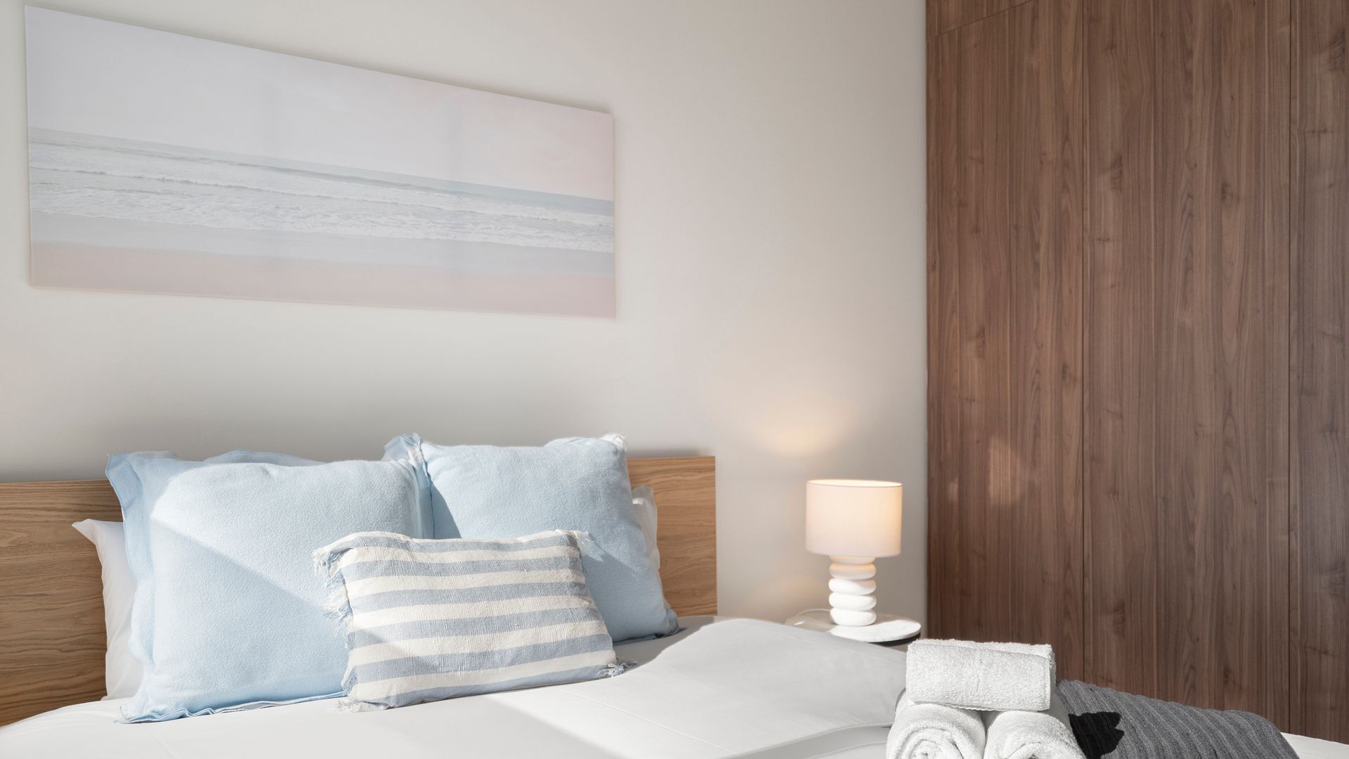 Une chambre d’hôtel avec un lit, des oreillers, une lampe et un mur recouvert de panneaux en bois.