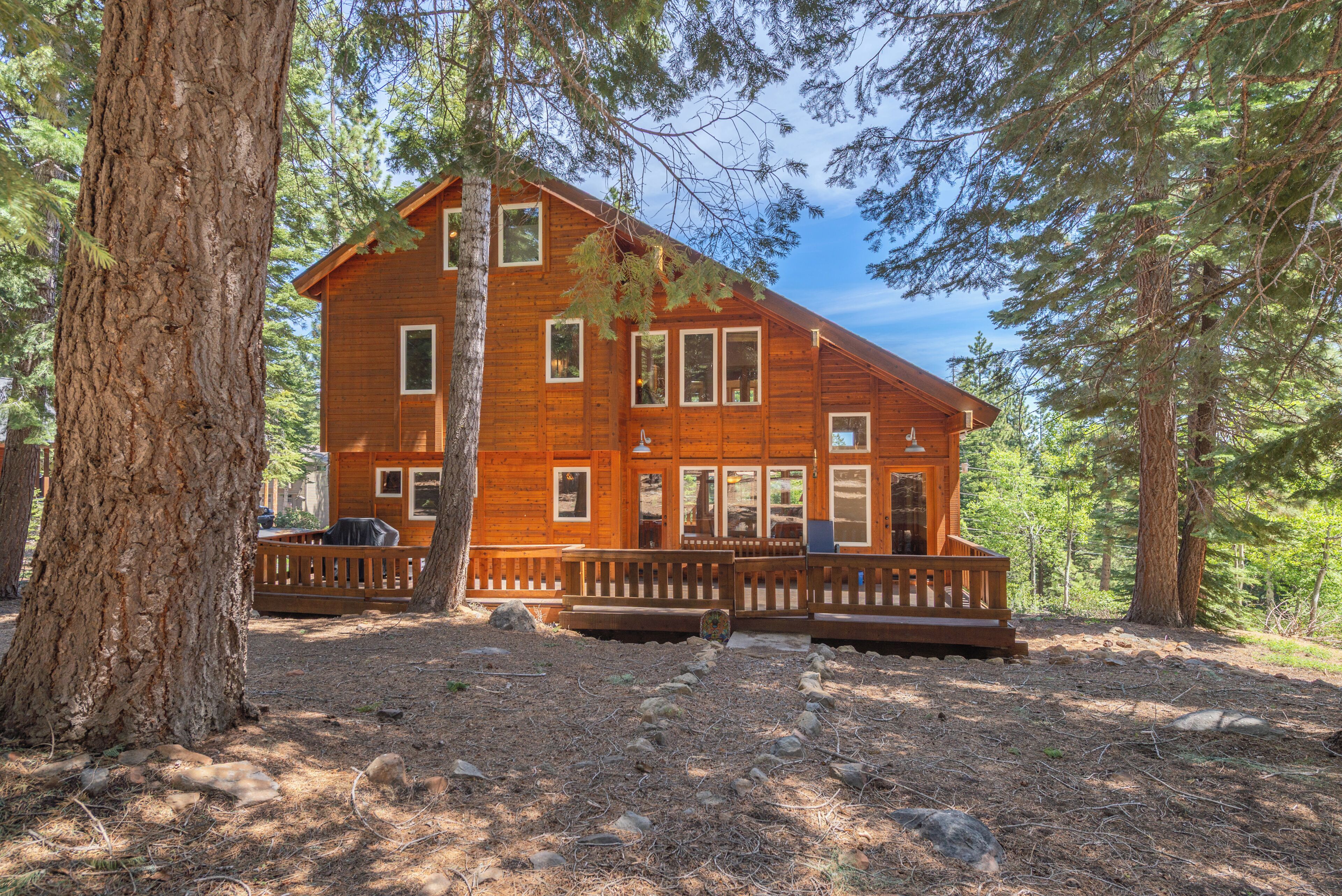 A wooden cabin with a porch, surrounded by trees.