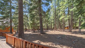 A forested area with wooden structures, including a cabin and a covered walkway. - New- Cozy Pathway Pines (Truckee)