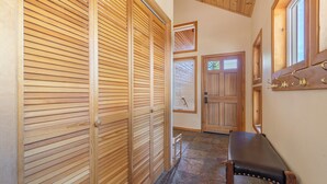 A hallway with wooden sliding doors, a bench, and a stone-tiled floor. - New- Cozy Pathway Pines (Truckee)