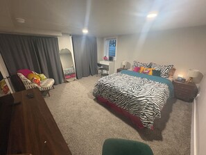 A bedroom with a bed, a desk, a chair, a mirror, and a nightstand. - #HabitueHomes - The Tigers Nap (Boise)