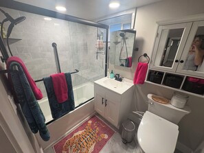 A modern bathroom with a glass shower enclosure, a white sink, a toilet, and a mirror above the sink. - #HabitueHomes - The Tigers Nap (Boise)