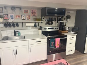 A modern kitchen with white cabinets, a stainless steel stove, and a microwave. - #HabitueHomes - The Tigers Nap (Boise)