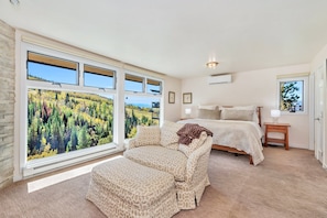 A bedroom with a large window, a bed, a nightstand, and a view of a forest. - FPX Legacy Lodge - One of a kind & Renovated! ~Ski In/Out~  Private HT, Club Amenities & EZCancel (Steamboat Springs)