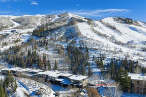 A ski resort with snow-covered slopes, a building with multiple floors, and a clear blue sky. - FPX Legacy Lodge - True Ski In Ski Out! 5-BR+Loft+Rec Room w/ Views, Private Hot Tub, Club Amenities (Steamboat Springs)