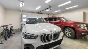 Eine Garage mit zwei Autos: einem weißen BMW und einem roten SUV, sowie einem Fahrrad.