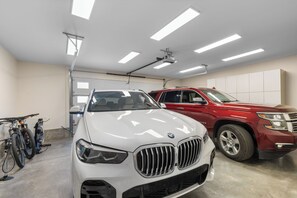A garage with two parked cars, a white BMW and a red SUV, and a bicycle. - FPX Legacy Lodge - True Ski In Ski Out! 5-BR+Loft+Rec Room w/ Views, Private Hot Tub, Club Amenities (Steamboat Springs)