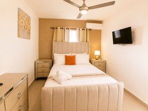 A hotel room with a bed, a ceiling fan, a TV, and a painting on the wall. - Perfect 3-bedroom apartment with AC in beautiful Santiago de los Caballeros (Santiago de los Caballeros)