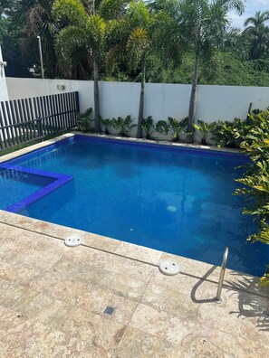A swimming pool with a tiled edge, a metal ladder, and a tiled deck. - Perfect 3-bedroom apartment with AC in beautiful Santiago de los Caballeros (Santiago de los Caballeros)
