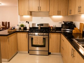 A modern kitchen with wooden cabinets, stainless steel appliances, and a black countertop. - Perfect 3-bedroom apartment with AC in beautiful Santiago de los Caballeros (Santiago de los Caballeros)