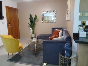 A living room with a sofa, a yellow chair, a coffee table, and a decorative vase. - Perfect 3-bedroom apartment with AC in beautiful Santiago de los Caballeros (Santiago de los Caballeros)