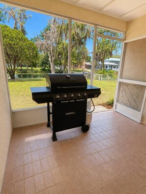 A black NexGrill barbecue grill in a room with large windows overlooking a grassy area and trees. - Luxury Gulf Access Retreat | Gym | Crystal River (Crystal River)