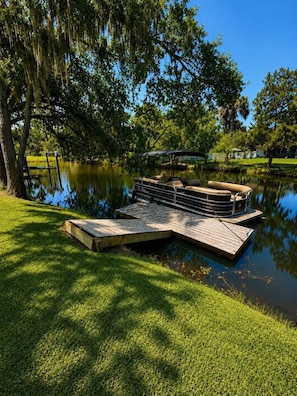 A dock extending into a calm body of water, surrounded by lush greenery and trees.