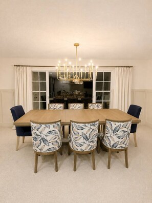 A dining room with a wooden table, six chairs with floral upholstery, and a chandelier. - Luxury Gulf Access Retreat | Gym | Crystal River (Crystal River)