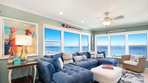Ein Wohnzimmer mit großem Fenster, Deckenventilator und Surf-Dekor.