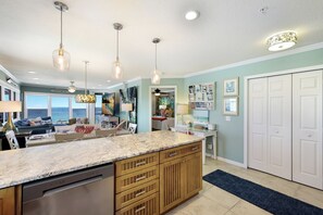 A modern kitchen with a large island, pendant lights, and a view to the outside. - Direct Beachfront | Coastal 3BR Retreat (Bradenton Beach)