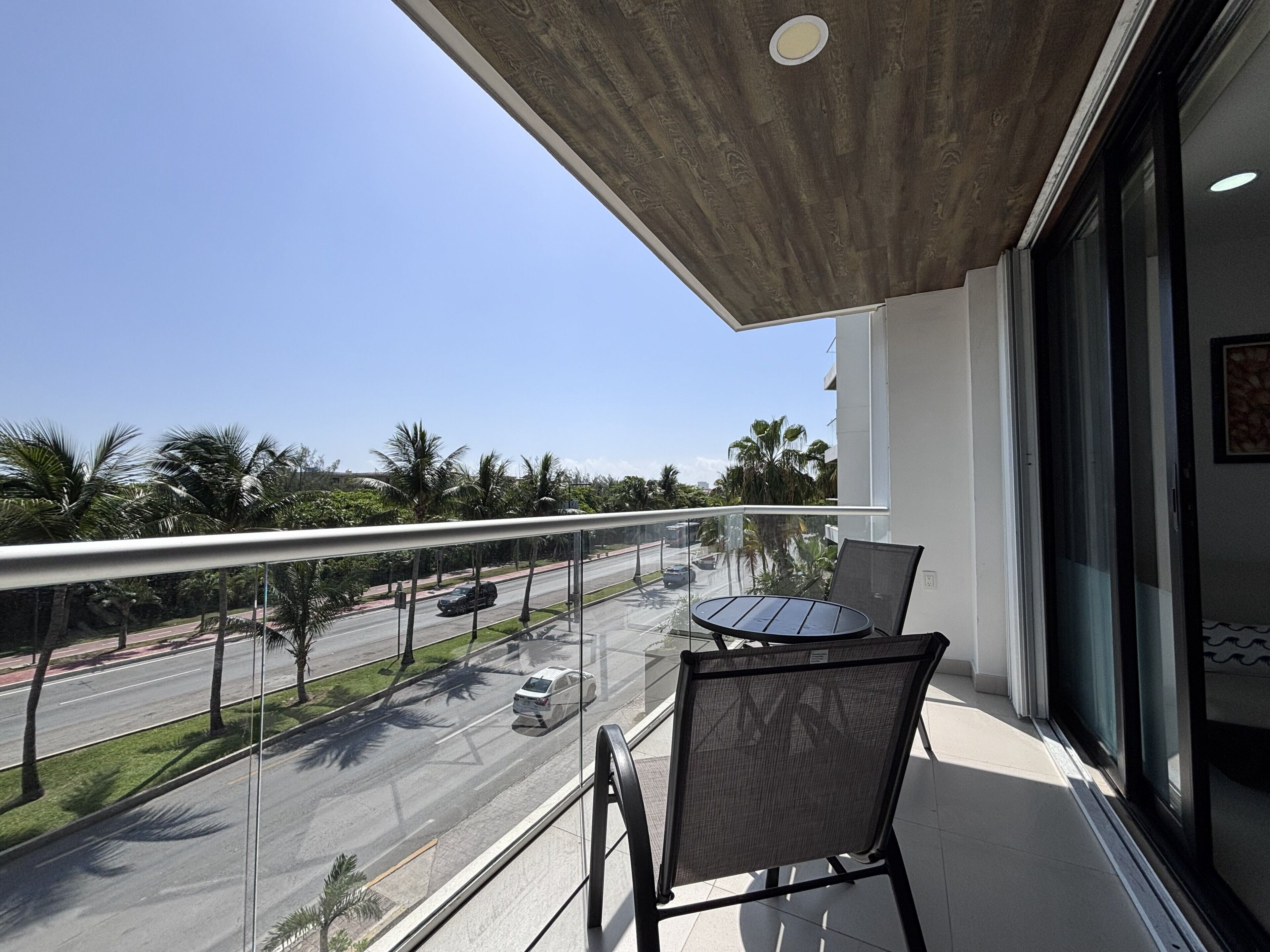 A balcony with a glass railing, a table, and two chairs.