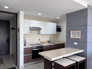 A modern kitchen with white cabinets, a stainless steel range hood, a built-in oven, and a countertop with a sink. - Delightful 2 bedroom Condo & Ocean View Rooftop& just across the beach (Cancún)