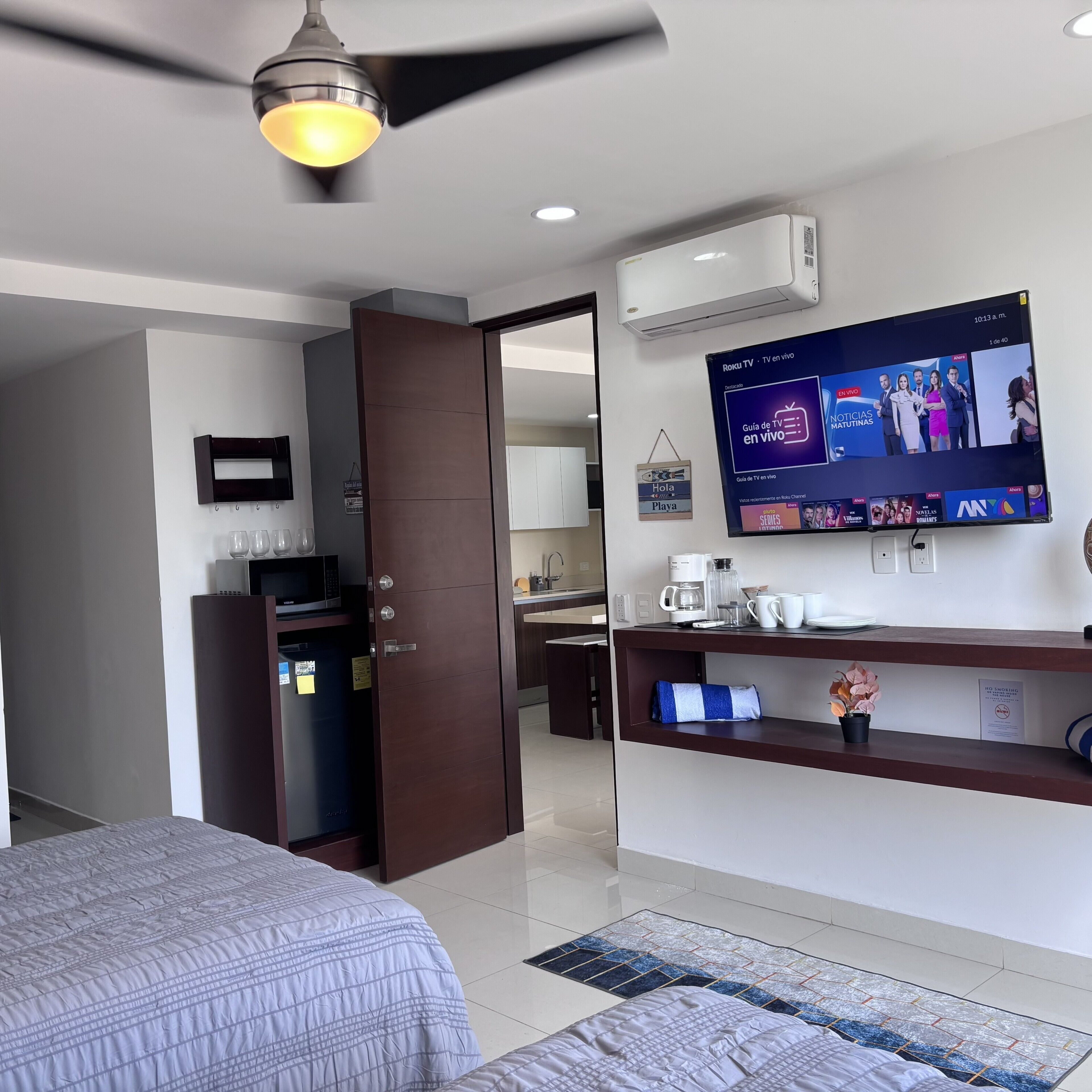 Een hotelkamer met een bed, een bureau met een flatscreen televisie, een koffiezetapparaat en een magnetron.