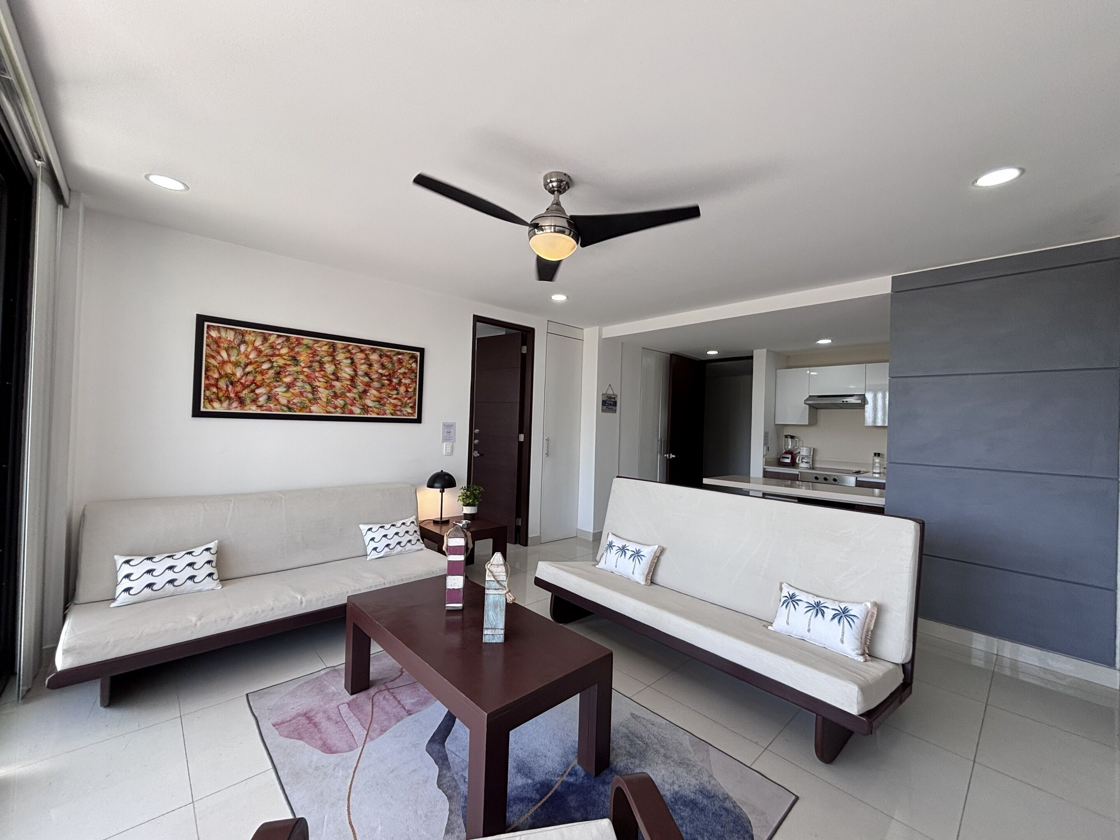 A modern living room with a sofa, a coffee table, and a ceiling fan.